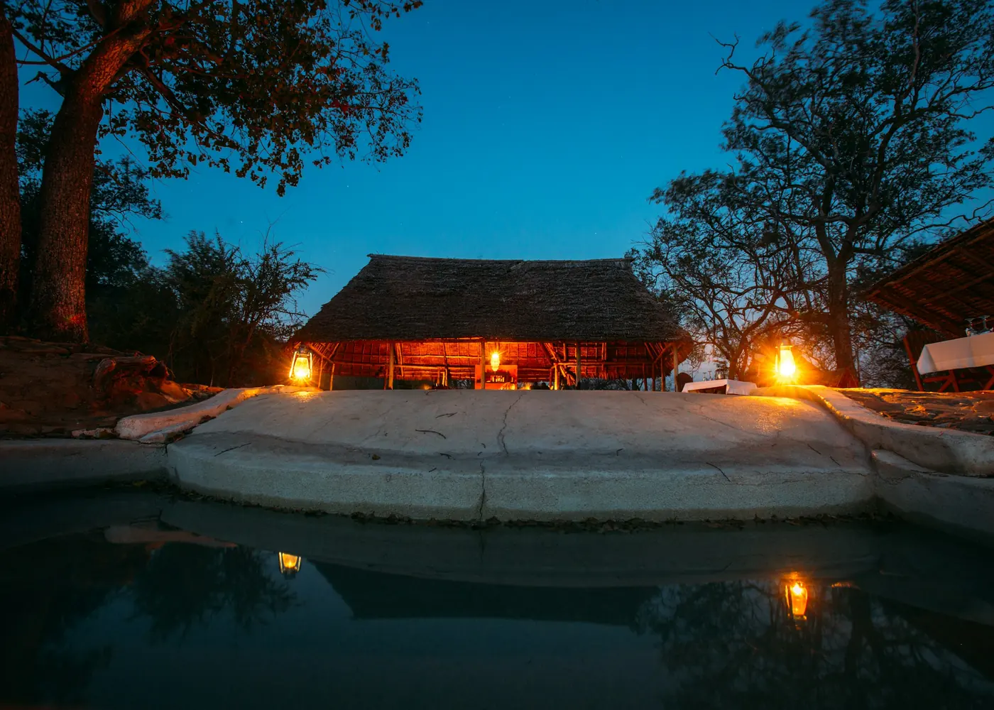 A camp and pool lit at dusk